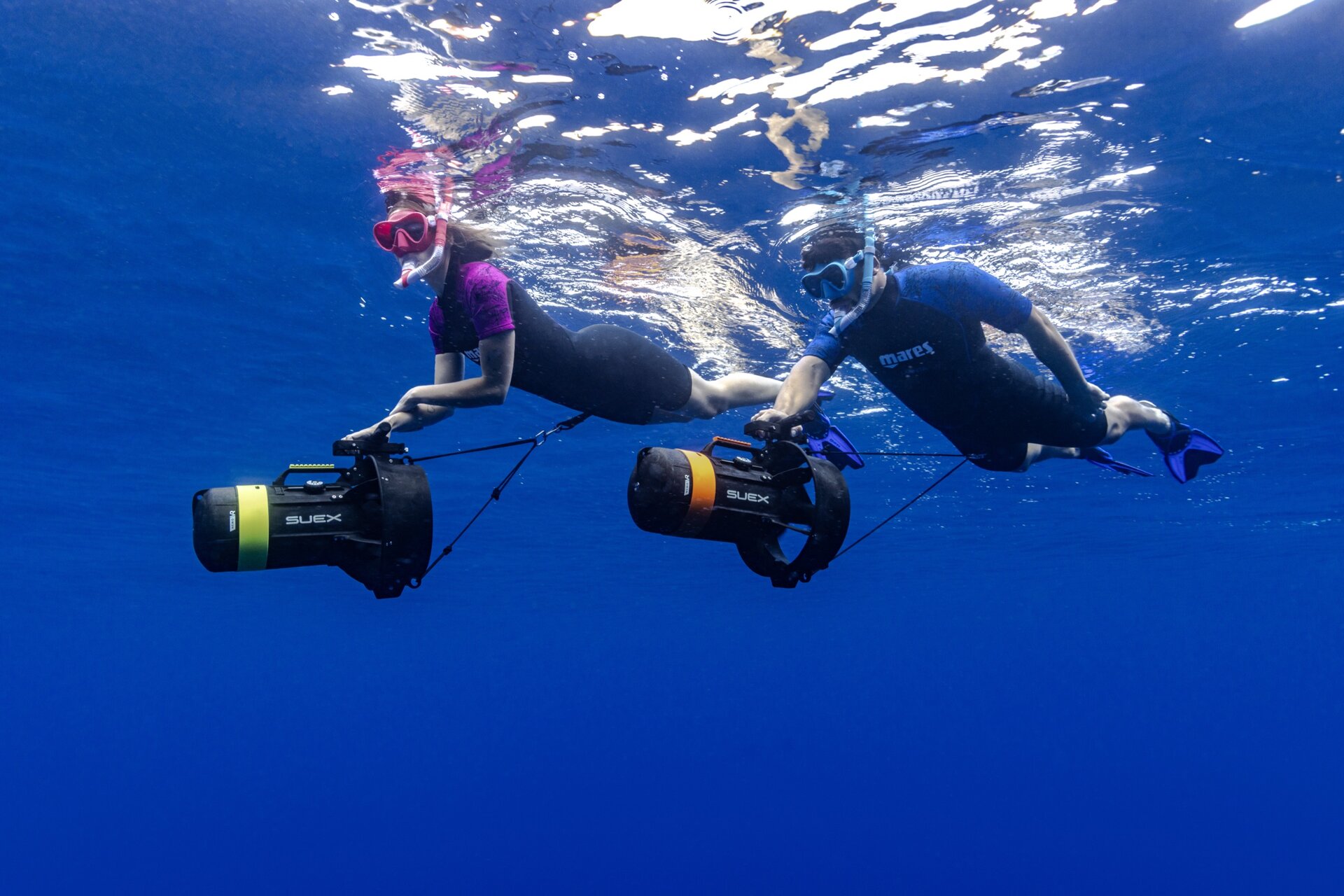 Two divers exploring on Suex dive scooters in clear blue water